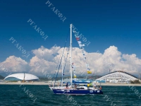 Участники I Международного яхтенного фестиваля «Черное море» проходят на яхте вдоль побережья Имеретинской бухты, на втором плане вид олимпийских спортивных арен. Российская Федерация, Краснодарский край, г. Сочи. 07.07.2013 г. РГАКФД. Арх. № 8-290-цв.